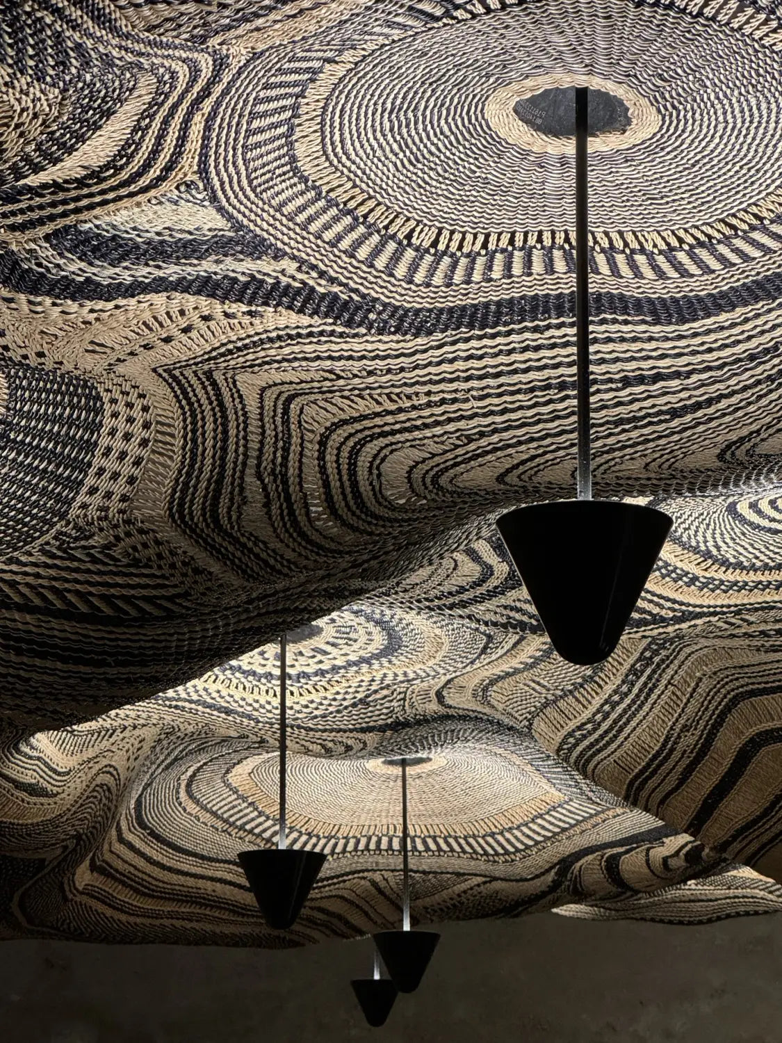 A detail of a sprawling light fixture produced by Ghanaian artisans in collaboration with PET Lamp with swirling, woven designs