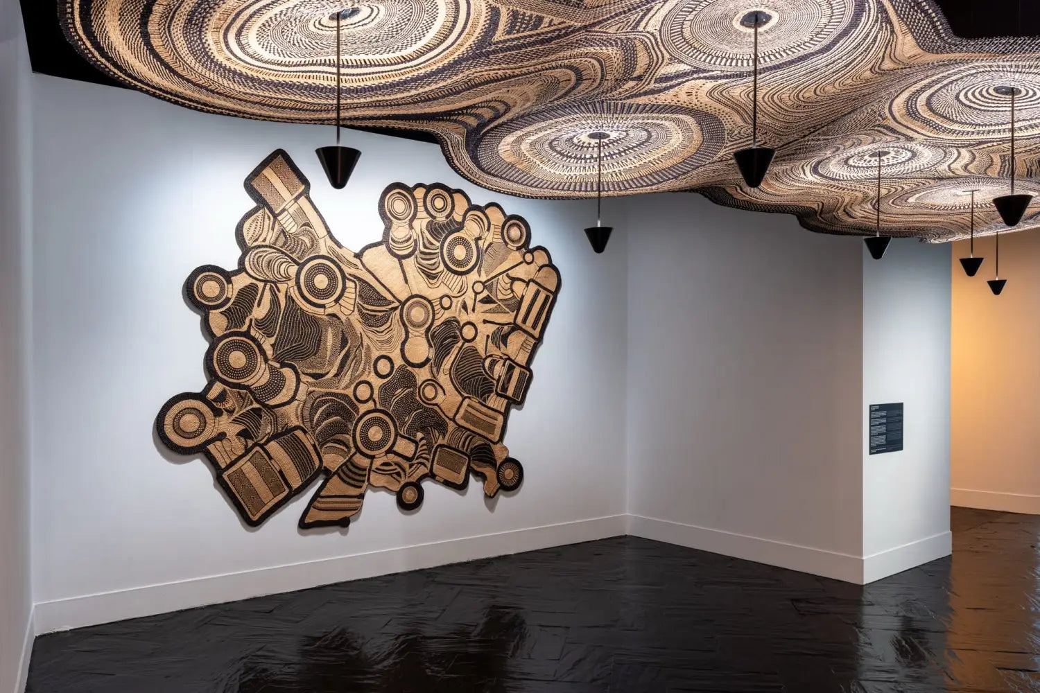 A detail of a sprawling light fixture produced by Ghanaian artisans in collaboration with PET Lamp with swirling, woven designs, with an additional piece installed on a wall